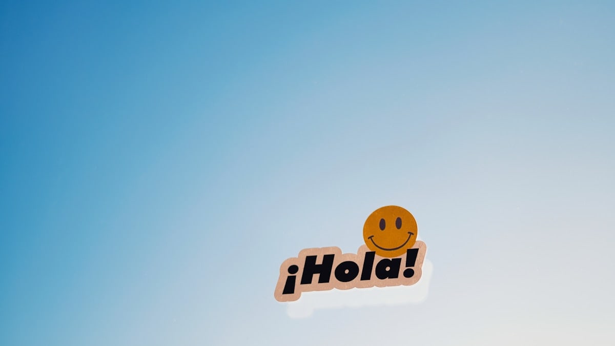 A smiley face sticker with the word hola